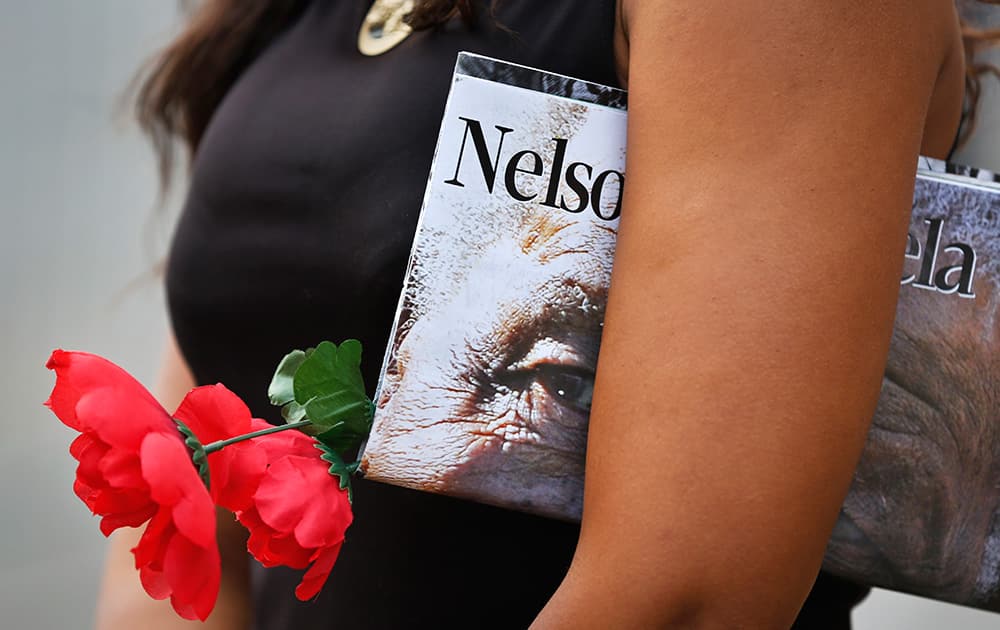 A mourner holding a flower waits for the procession for former South African president Nelson Mandela to make its way through the streets of Pretoria, South Africa.