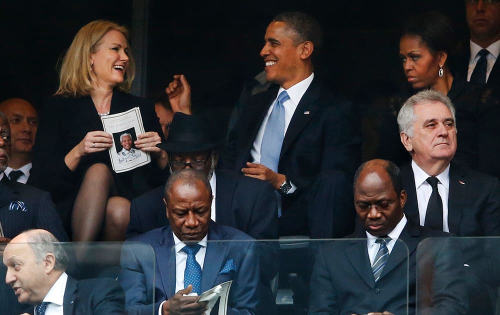 President Barack Obama jokes with Danish prime minister, Helle Thorning-Schmidt as first lady Michelle Obama looks on at right during the memorial service for former South African president Nelson Mandela at the FNB Stadium in Soweto, near Johannesburg, South Africa.