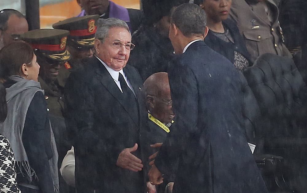 US President Barack Obama shakes hands with Cuban President Raul Castro at the FNB Stadium in Soweto, South Africa, in the rain for a memorial service for former South African President Nelson Mandela.
