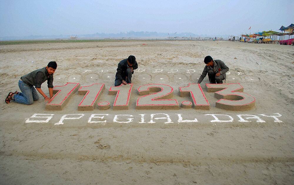 Students making sand art to mark the special date `11.12.13` (Wednesday) on the banks of river Ganga in Allahabad.