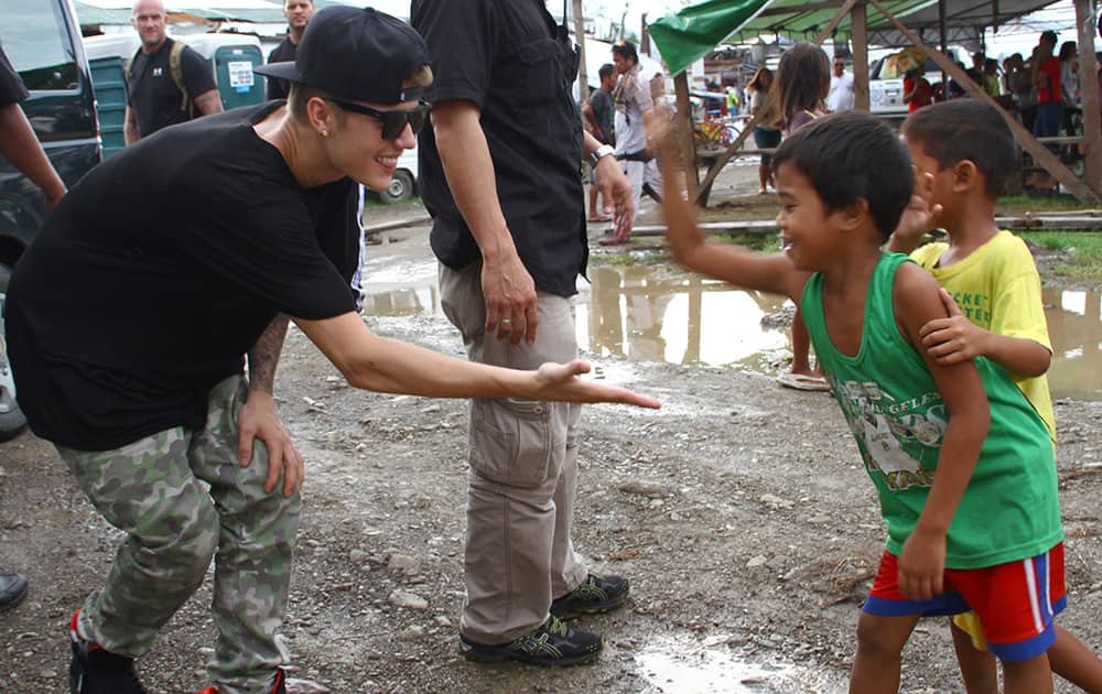 Justin Bieber exchanges high-fives with children survivors of typhoon Haiyan during his visit to Tacloban city, Leyte province in central Philippines.