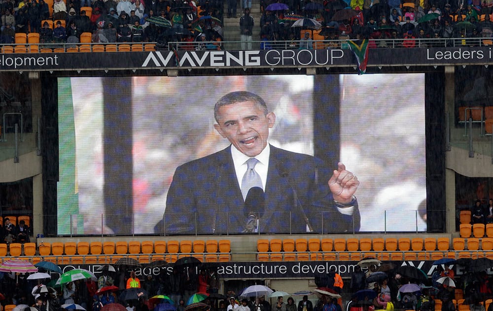 An image of President Barrack Obama is flashed on a screen as he makes his speech during the memorial service for former South African president Nelson Mandela at the FNB Stadium in Soweto, near Johannesburg, South Africa.