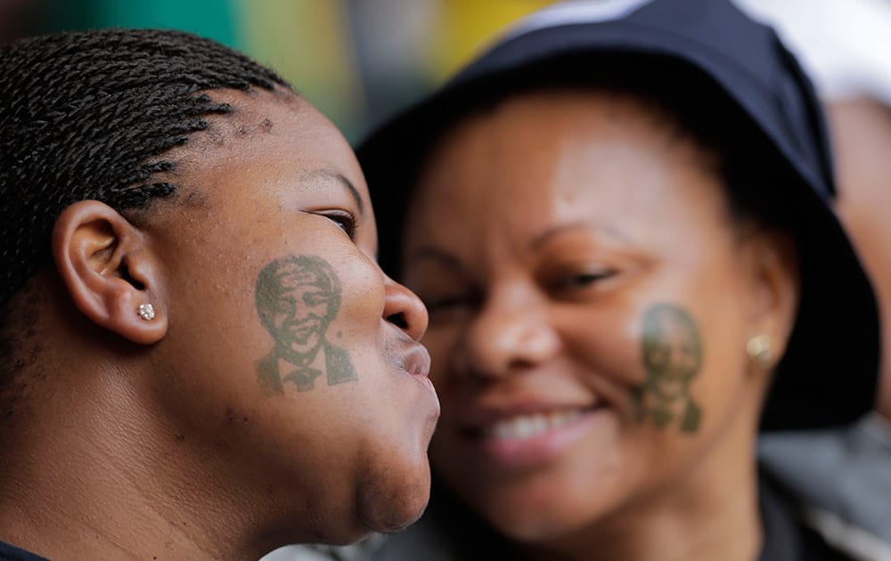 Women with tattoos of former South African president Nelson Mandela on their faces smile as they arrive for his memorial service at the FNB Stadium in Soweto, near Johannesburg.