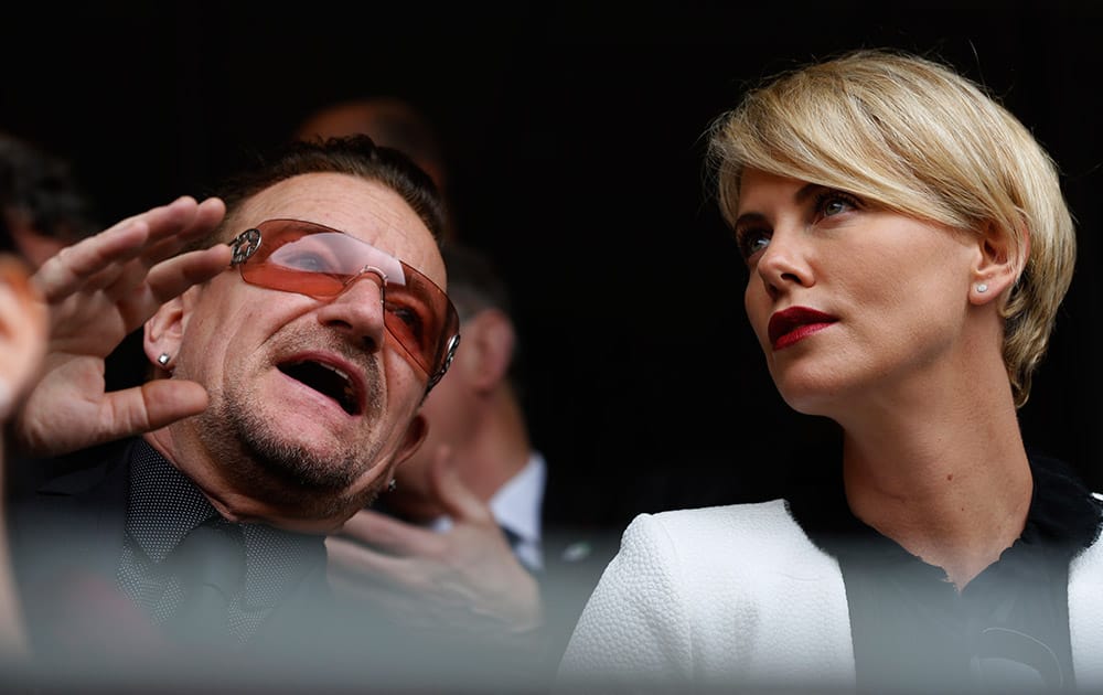 Actress Charlize Theron speaks with musician Bono before the memorial service for former South African president Nelson Mandela at the FNB Stadium in Soweto near Johannesburg.