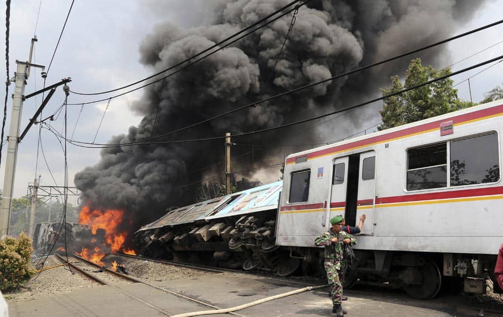 An Indonesian soldier walks away from the fire after a commuter train collided with a truck hauling fuel on the outskirts Jakarta.