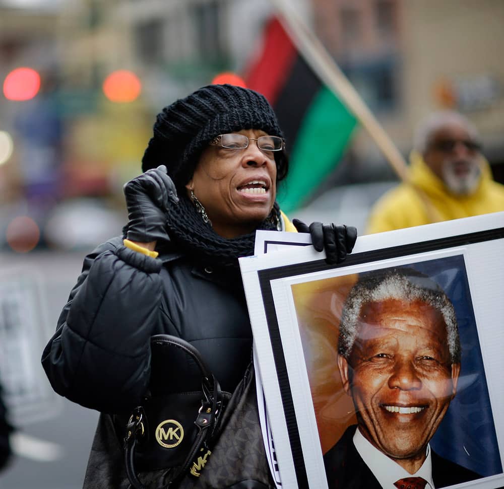 Barbara King, of Newark, holds a large photograph of Nelson Mandela, as a large group marches in remembrance for South African leader Nelson Mandela in downtown Newark, N.J.