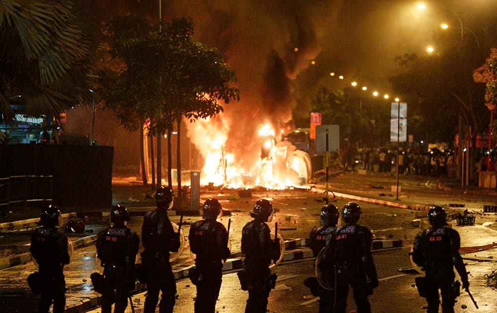Riot police stand guard as a vehicle goes up in flames after a riot broke out in Singapore`s Little India. A rare riot broke out in the Little India neighborhood apparently after a Bangladeshi worker was hit and killed by a bus, a local television channel reported.