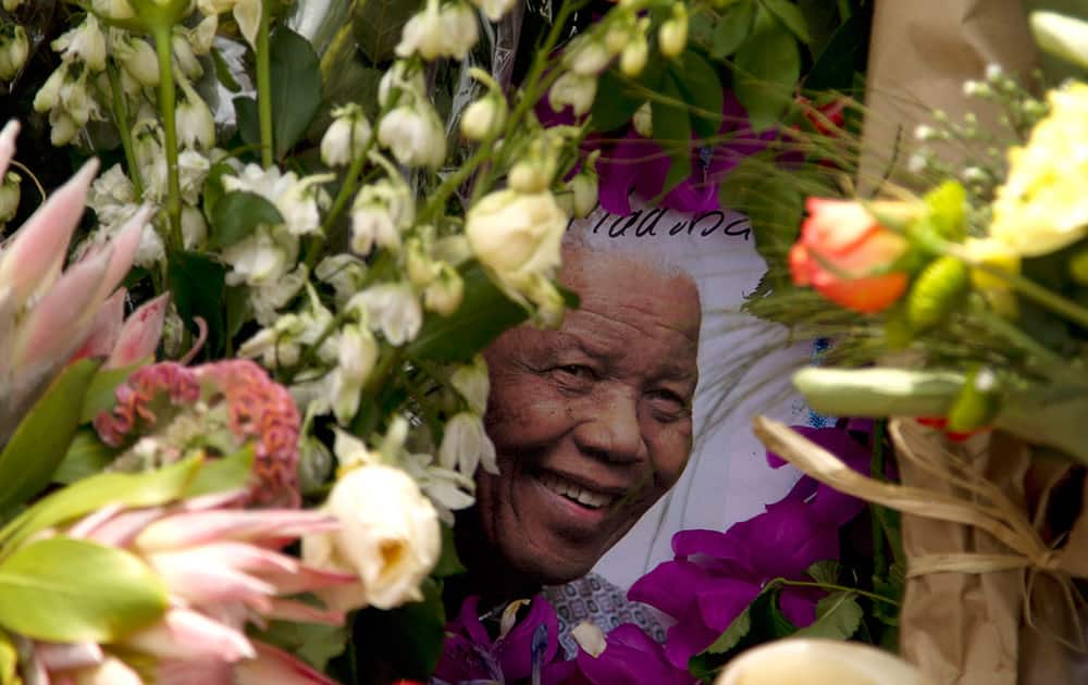 A picture of South Africa`s former president Nelson Mandela is seen placed in a pile of flowers outside his home in Johannesburg, South Africa.