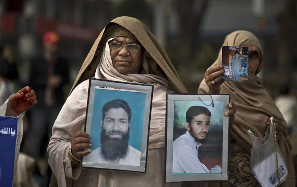 Pakistani Delshad Fazil, 60, holds photographs of her missing son, left, and nephew, during a protest near the parliament in Islamabad, Pakistan.