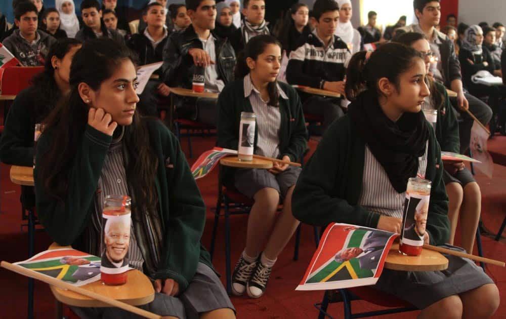 Lebanese students with South Africa flags and candles with the portraits of late South African leader Nelson Mandela on their desks listen to a lecture on his life at their school, in the southern port city of Sidon, Lebanon.