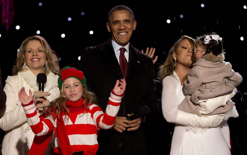 Soprano Renee Fleming, President Barack Obama, and singer and songwriter Mariah Carey holding her daughter Monroe, stand on stage together at the end of the 2013 National Christmas Tree Lighting ceremony at the Ellipse near the White House in Washington.