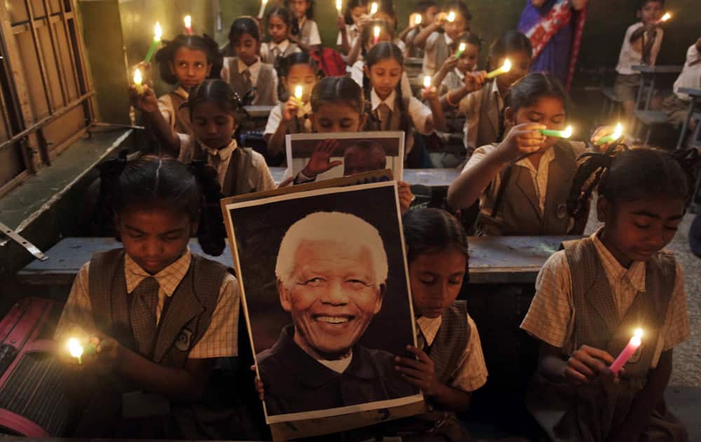 Young Indian schoolchildren hold candles and portrait of former South African President Nelson Mandela as they pay tribute to him on hearing of his death, at a school in Ahmadabad.