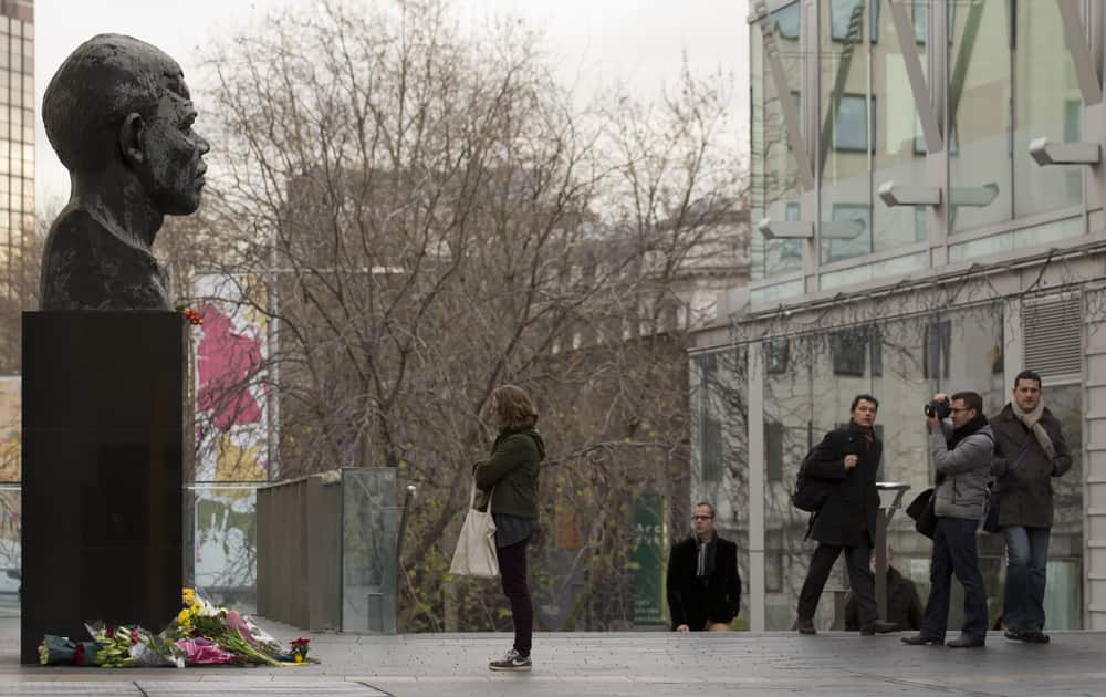 Members of the public stand by a statue of former South African president Nelson Mandela, at the side of the Royal Festival Hall on the south bank of London.