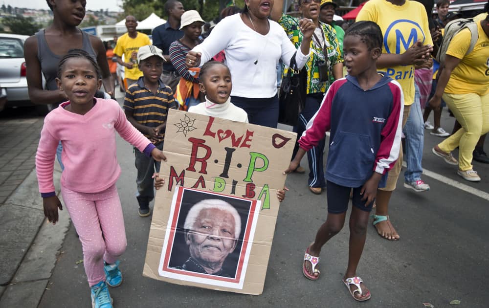A young girl with a placard showing the face of Nelson Mandela and referring to his clan name