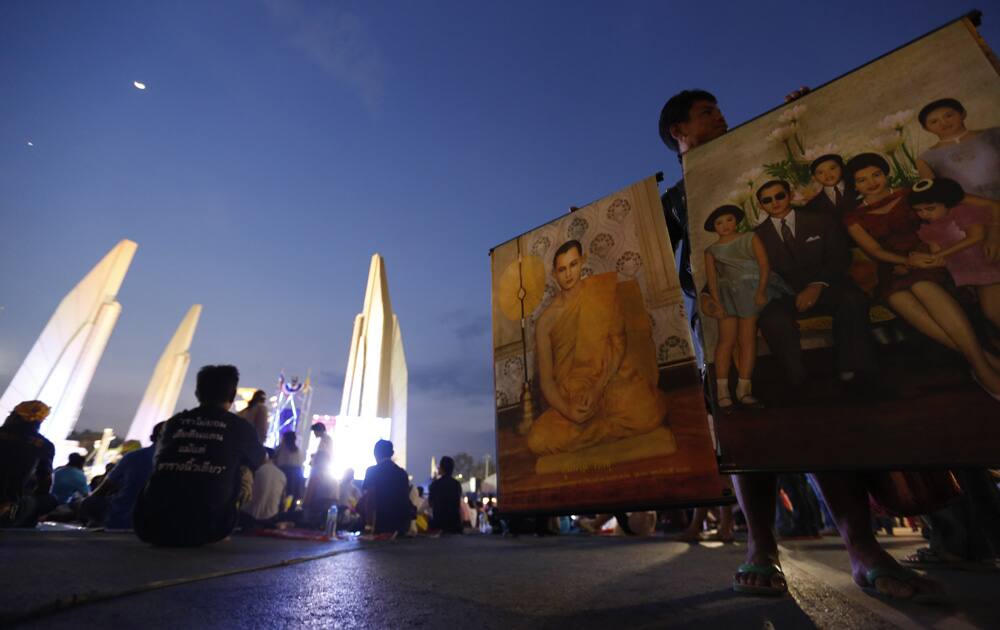 A vendor holds photos of Thai King Bhumibol Adulyadej as anti-government protesters gather at the Democracy Monument in Bangkok, Thailand.