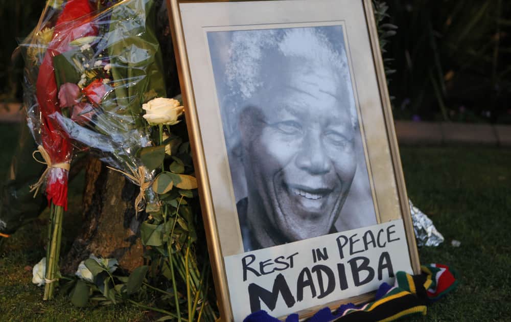 A framed portrait of former president Nelson Mandela and flowers are placed outside Mandela`s Johannesburg home after the freedom fighter passed away Thursday night after a long illness.