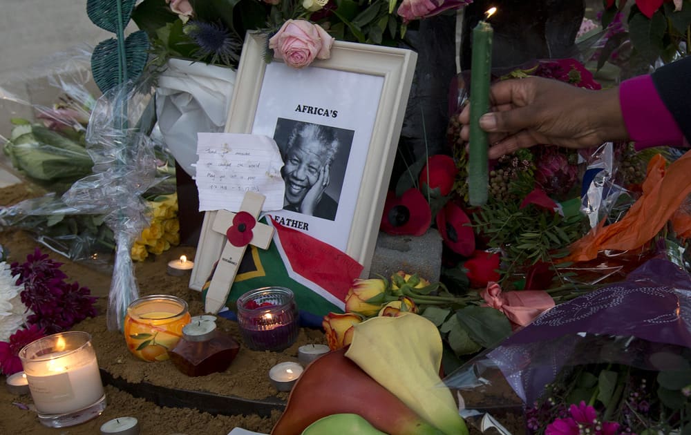 A candle is put amongst floral tributes laid in memory of former South African president Nelson Mandela, beside his statue in Parliament Square, London.