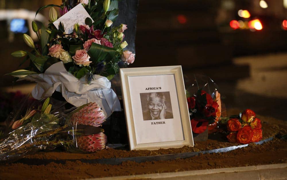 Floral tributes and a picture are left at a statue of Nelson Mandela at Parliament Square in London.