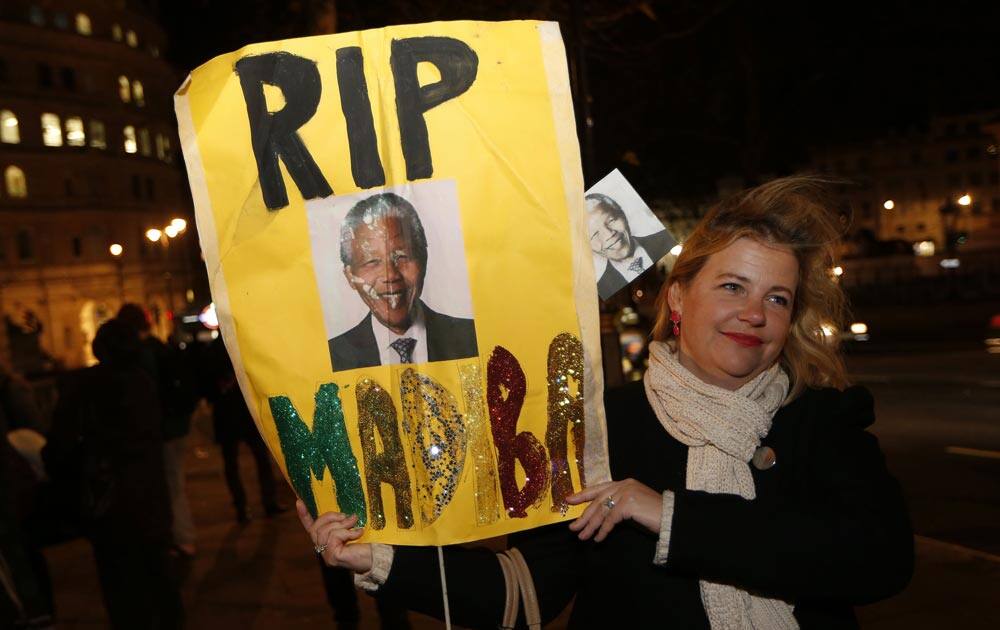 A woman with a banner pays tribute to Nelson Mandela outside South African High Commission in London.