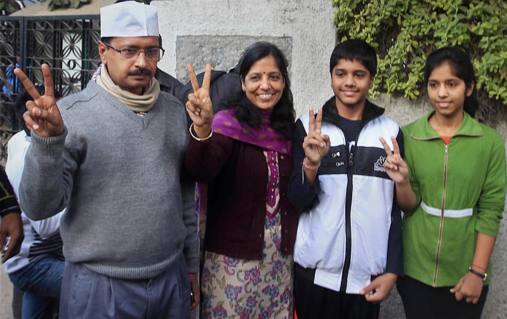 AAP convener Arvind Kejriwal flashes victory sign with his family after casting vote for Delhi Assembly elections, at a polling booth in New Delhi.