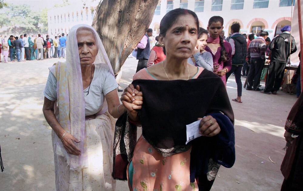 An elderly woman voter leaves after casting her vote at a polling station for Delhi Assembly elections, at Chhatarpur in New Delhi.