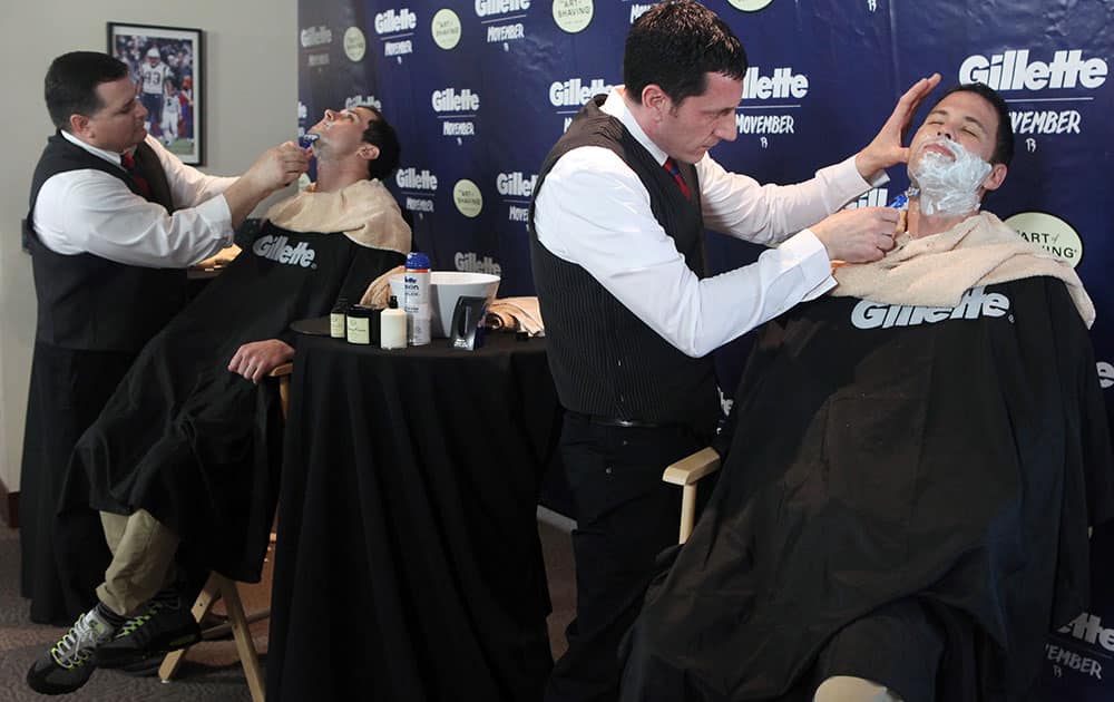 New England Patriots fan Tim Sullivan, right, and Patriots wide receiver Danny Amendola, left, say goodbye to their Mo`s with help from barbers from The Art of Shaving at Gillette Stadium in Foxborough, Mass.