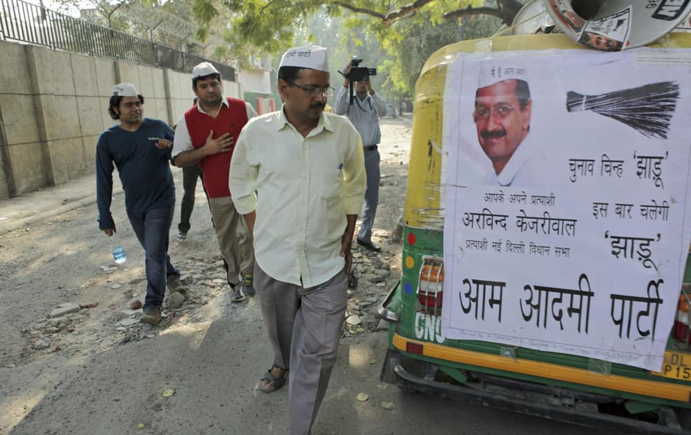 Arvind Kejriwal looks at an auto rickshaw displaying a poster in support of his party, ahead of the Delhi state assembly elections in New Delhi.