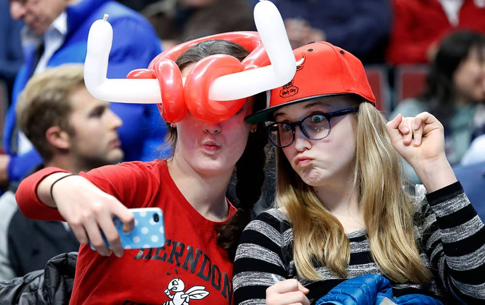 Saunders Ervin, left, and Samantha Walter, of Chicago, make a cellular phone portrait of themselves during the first half of an NBA basketball game between the Chicago Bulls and the New Orleans Pelicans, in Chicago.