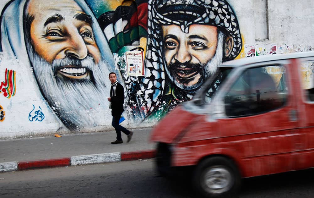 A Palestinian walks past a mural depicting the late Palestinian leader Yasser Arafat, center, and the late Hamas leader Sheik Ahmad Yassin in Gaza City.