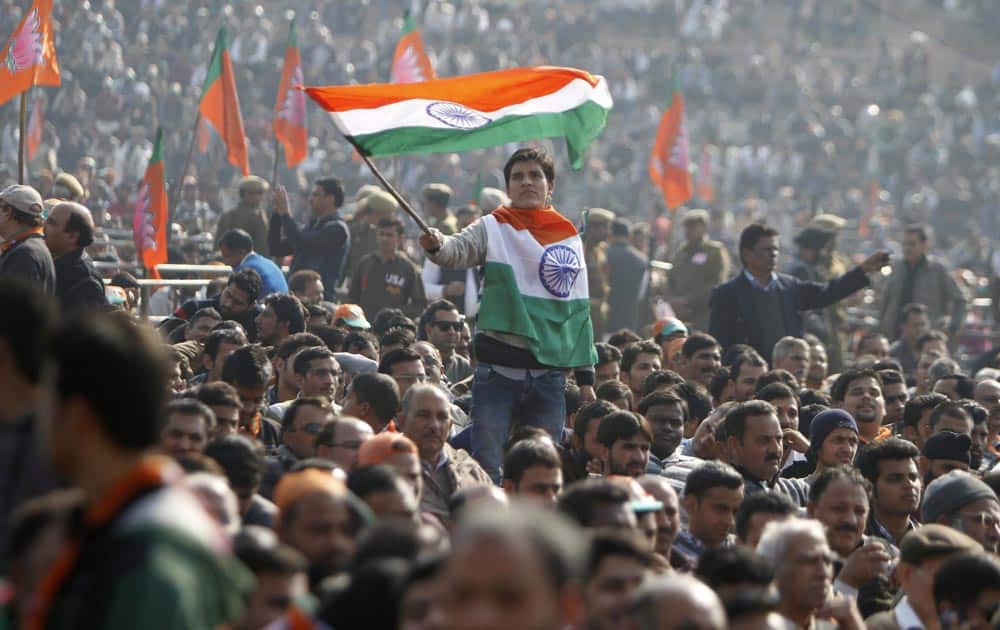 A supporter of India`s main opposition Bharatiya Janata Party (BJP) waves an Indian flag as they wait to listen to their leader Narendra Modi at a rally in Jammu.