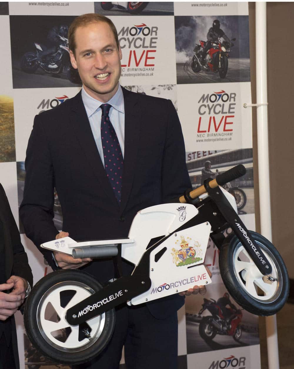 Britain`s Prince William, the Duke of Cambridge, receives a gift for his son Prince George from exhibition director Dean Linehan during his visit to Motorcycle Live at the National Exhibition Centre, Birmingham.
