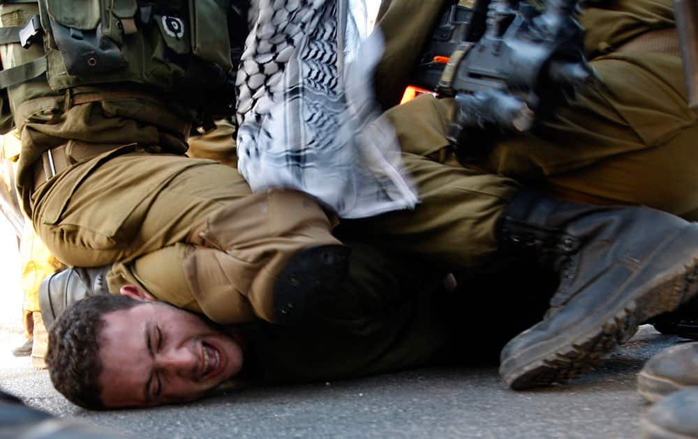 A Palestinians activist is detained by Israeli soldiers during a protest against the Prawer Plan to resettle Israel’s Palestinian Bedouin minority from their villages in the Negev Desert, near the Israeli settlement of Bet El, north of the West Bank city of Ramallah.