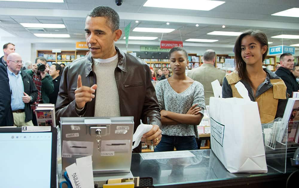 President Barack Obama, with daughters Sasha, center, and Malia, pays for his purchase the the local bookstore Politics and Prose in northwest Washington.