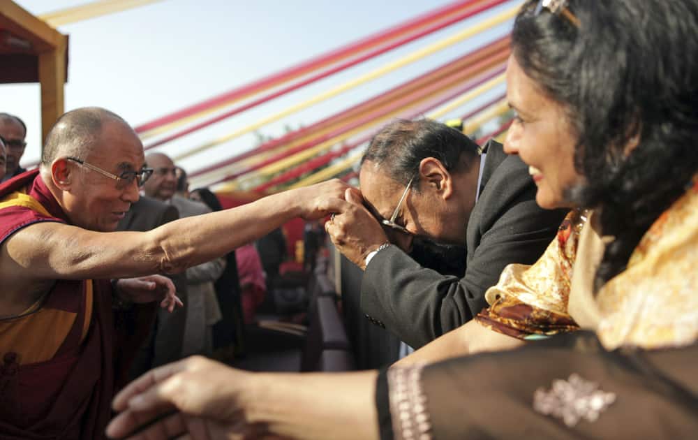 A man takes the hand of Tibetan spiritual leader the Dalai Lama respectfully to his forehead as the latter arrives to give a talk at Apollo Hospital in New Delhi.