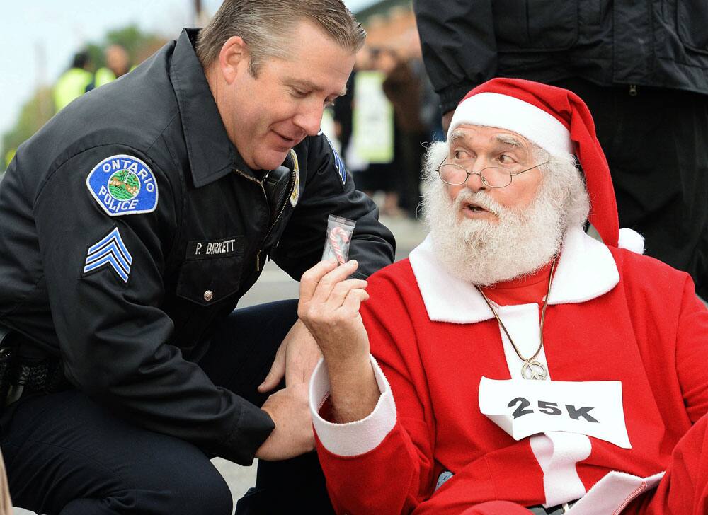 Wal-Mart protester Karl Hilgert, dressed as Santa Claus, hands Ontario police department Sgt. Pat Birkett a candy cane as Hilgert is read his rights before being arrested for failure to disperse after sitting down with nine other protesters in the middle of an intersection, in Ontario, Calif.