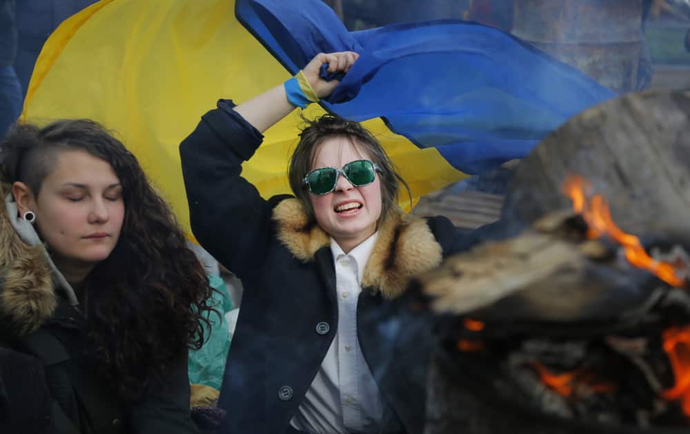 Ukrainian girls react to the smoke from the iron barrel with a fire during a rally in support of Ukraine`s integration with the European Union in the center of Kiev, Ukraine.