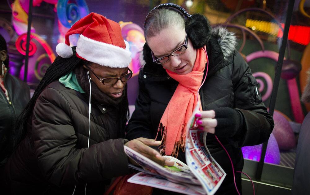 Shoppers browse a sale circular as they wait on line outside the Times Square Toys R` Us, in New York.