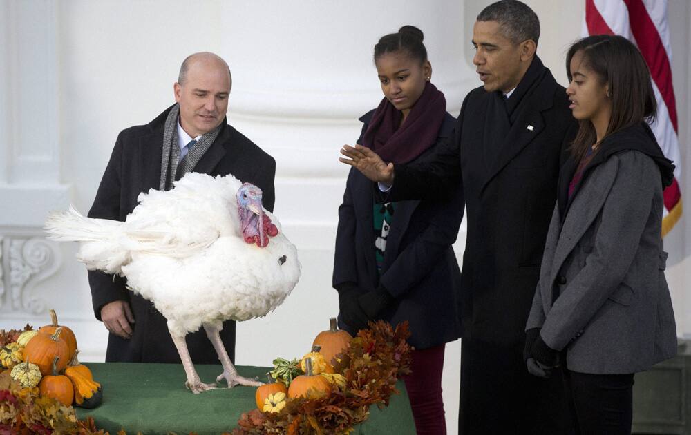 President Barack Obama, with daughters Sasha and Malia, carries on the Thanksgiving tradition of saving Popcorn the turkey from the dinner table.