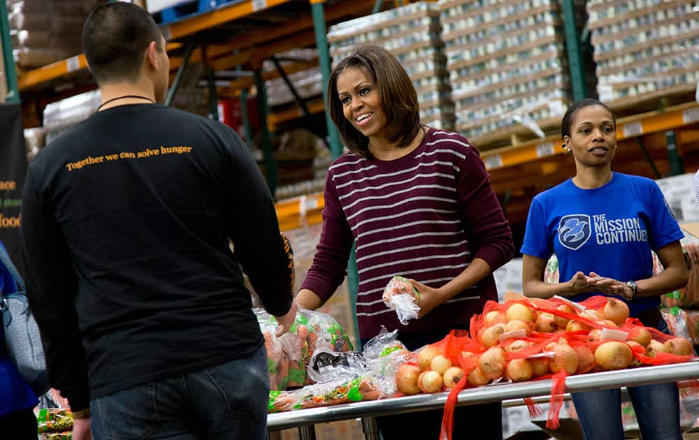 First lady Michelle Obama smiles as she participates in a Thanksgiving service project by handing out food at the Capital Area Food Bank in Washington. The Capital Area Food Bank distributes 30 million pounds of food annually.