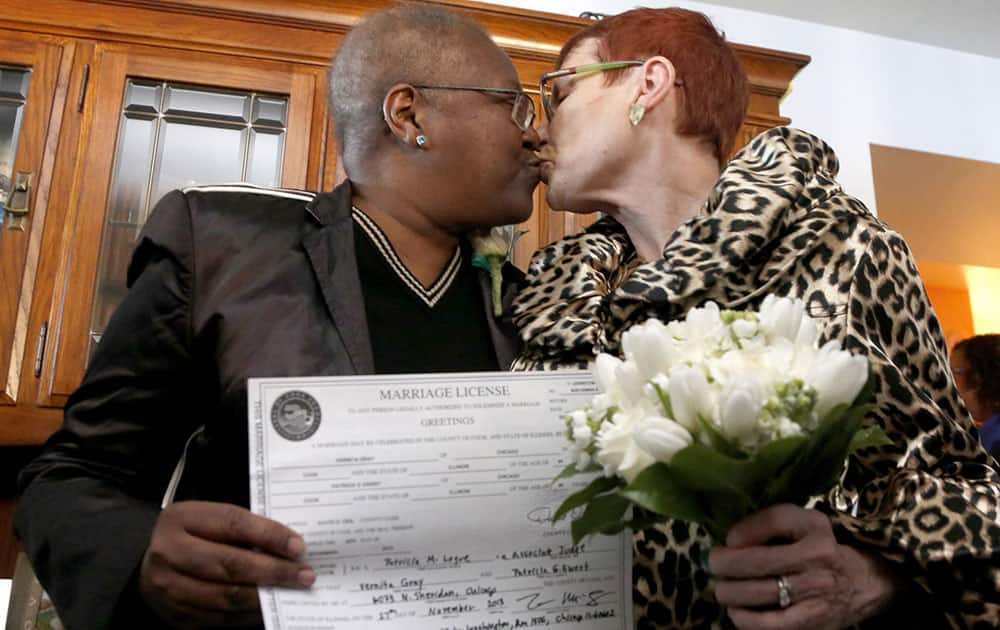 Holding their Illinois marriage license, Vernita Gray, left, and Patricia Ewert kiss after they were married by Cook County Judge Patricia Logue, the first gay marriage in Illinois, at the couple`s home in Chicago.