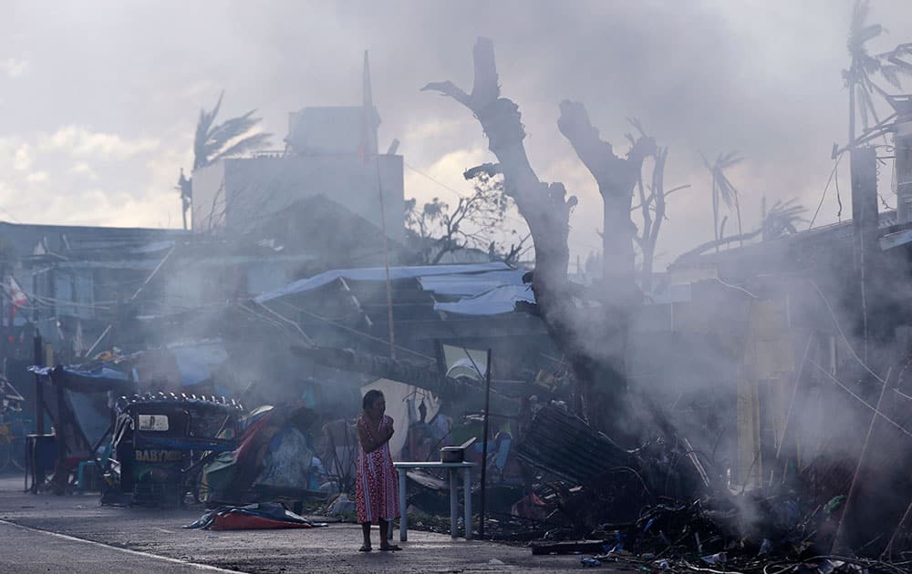 A typhoon survivor stands amid morning cooking smoke on the roadside in typhoon-ravaged Palo township, Leyte province in central Philippines.