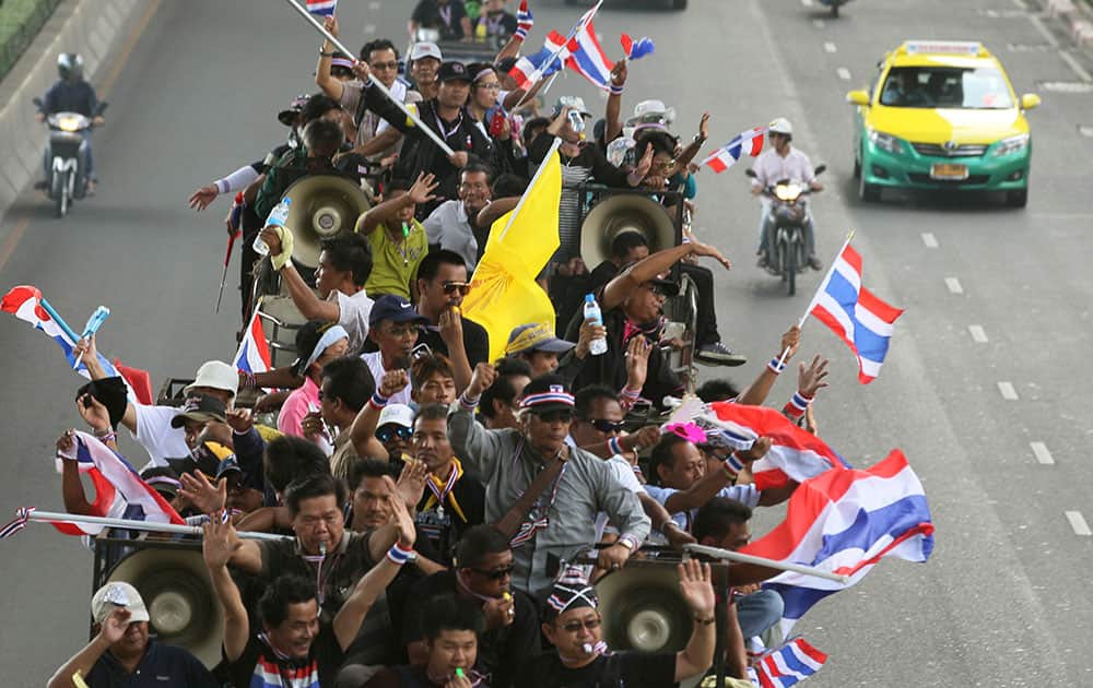 Anti-government protesters riding on a truck wave Thai national flags on their way to the Industry Ministry in Bangkok, Thailand, Wednesday, Nov. 27, 2013 Protesters vowing to topple Thai Prime Minister Yingluck Shinawatra took to the streets for a fourth straight day on Wednesday, declaring they would take over