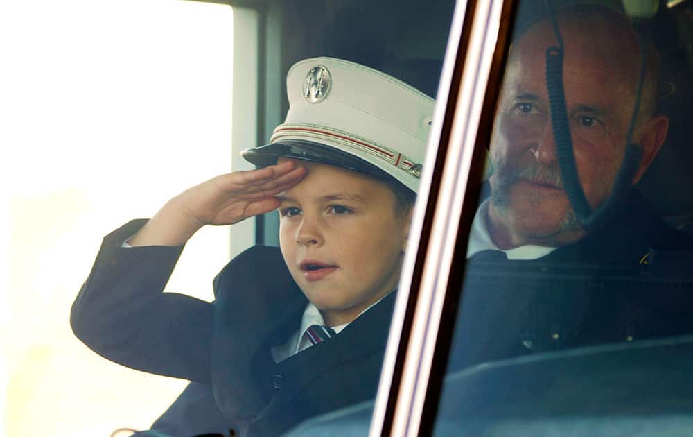 Jack Erickson, the son of Brandon Erickson, salutes firefighters as he sits on the lap of family friend Capt. Scott Kiesig in the Eagle fire truck that was transporting the casket of his father following the Tuesday, Nov. 26, 2013 memorial service at Eagle Christian Church in Eagle, Idaho.
