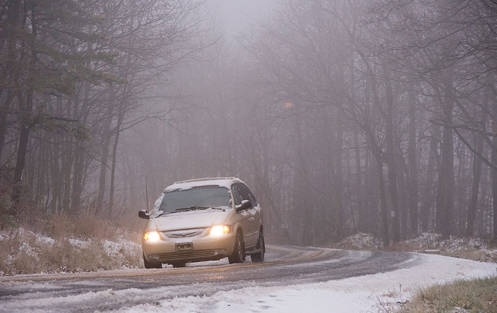 A car travels on Snake Road in Conyngham Township, Pa., as a mixture of rain, freezing rain and sleet fall heavily throughout the area.
