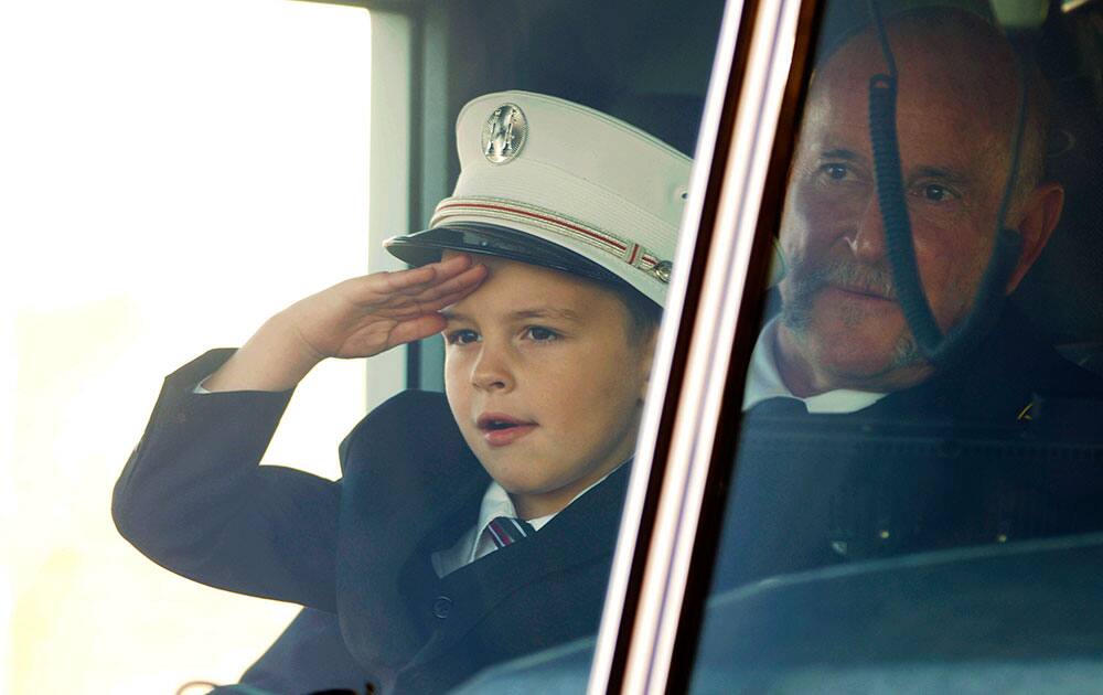 Jack Erickson, the son of Brandon Erickson, salutes firefighters as he sits on the lap of family friend Capt. Scott Kiesig in the Eagle fire truck that was transporting the casket of his father following the Tuesday, Nov. 26, 2013 memorial service at Eagle Christian Church in Eagle, Idaho.