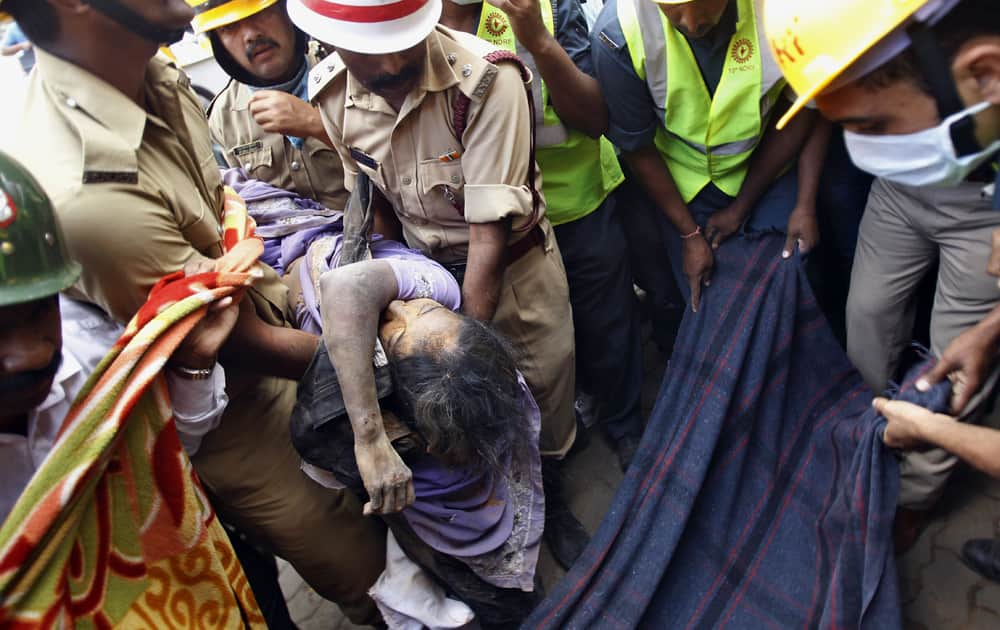 Firemen carry the body of Padma, 45, recovered from the debris of a collapsed house in Bangalore. Five persons including a 18-month old girl were buried alive when their house collapsed after incessant rains over the last few days, authorities said.