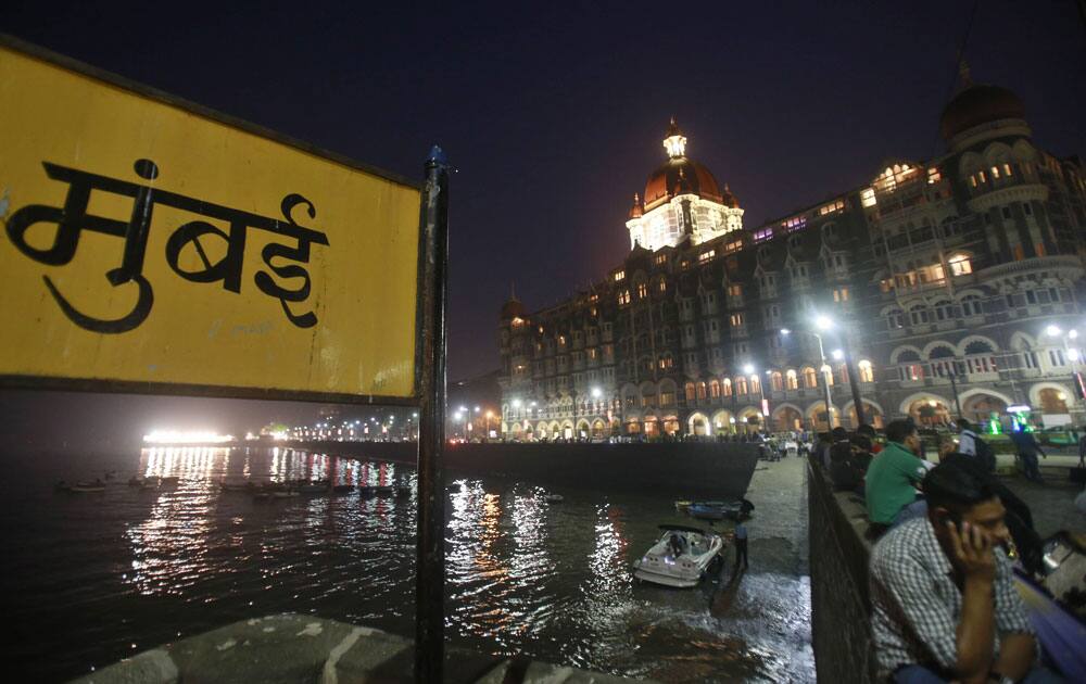 People sit on a promenade outside the Taj Mahal Palace hotel, one of the sites of the 2008 terror attack, on the eve of its fifth anniversary in Mumbai.