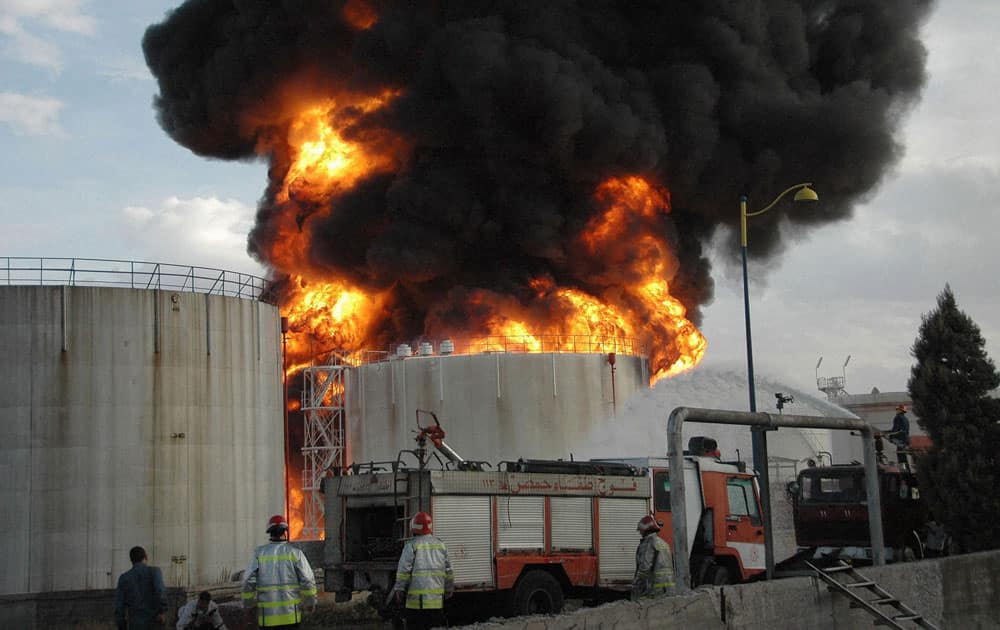 Syrian firefighters extinguish a fuel tank that was burned by rebels shelling according to SANA, at fuel refinery, in Homs, Syria.