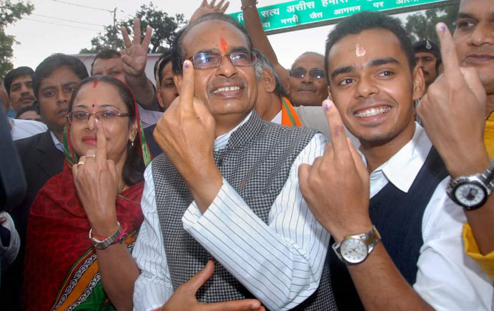 Madhya Pradesh Chief Minister Shivraj Singh Chauhan with his wife Sadhna Singh (L) and son Kartikey Singh Chouhan (R) showing their marked fingers after casting votes for Assembly elections at Jait village in Sehore, Madhya Pradesh.