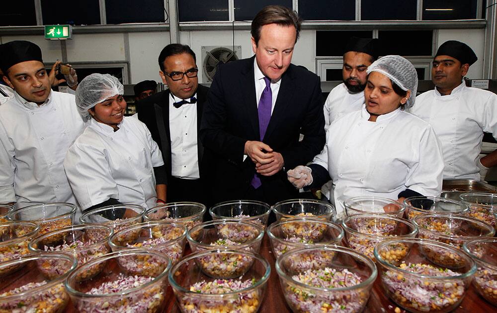 British Prime Minister David Cameron, center right, is being shown around the kitchen by founder of British Curry Awards, Enam Ali, center left, as he arrives at the British Curry Awards ceremony at Battersea Park in London.